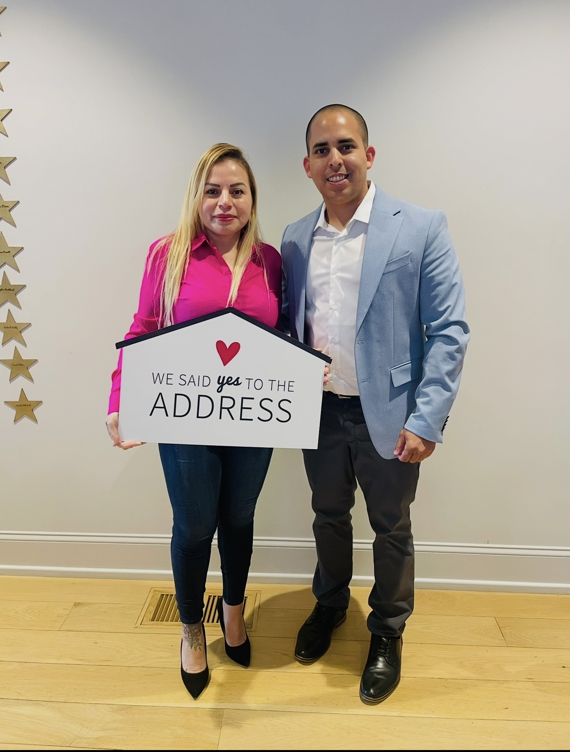 Ada Rastegar y Carlos Castro el dia del cierre de su primera vivienda, sosteniendo un letrero que dice We said yes to the address